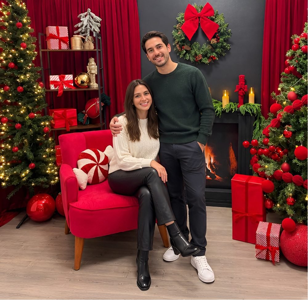 Pareja posando en el set navideño junto al sillón rojo