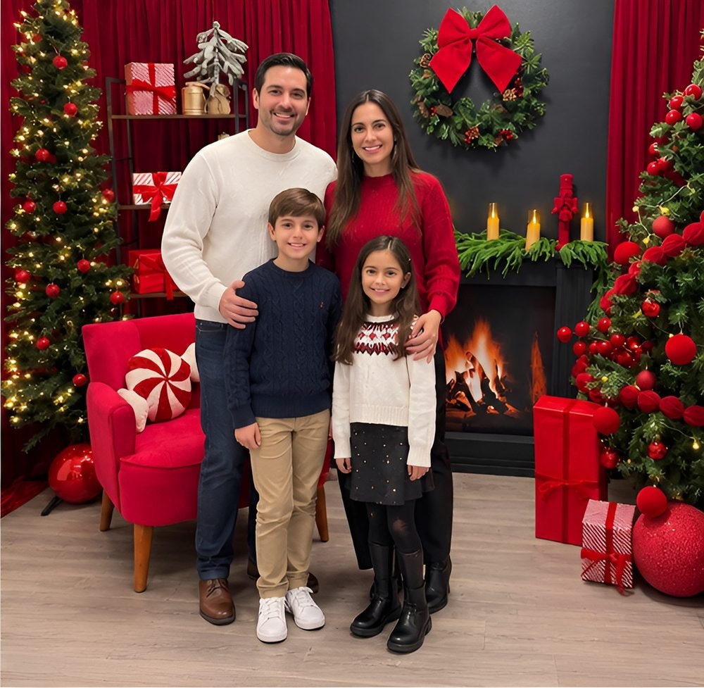 Familia con dos hijos frente a la chimenea del set navideño